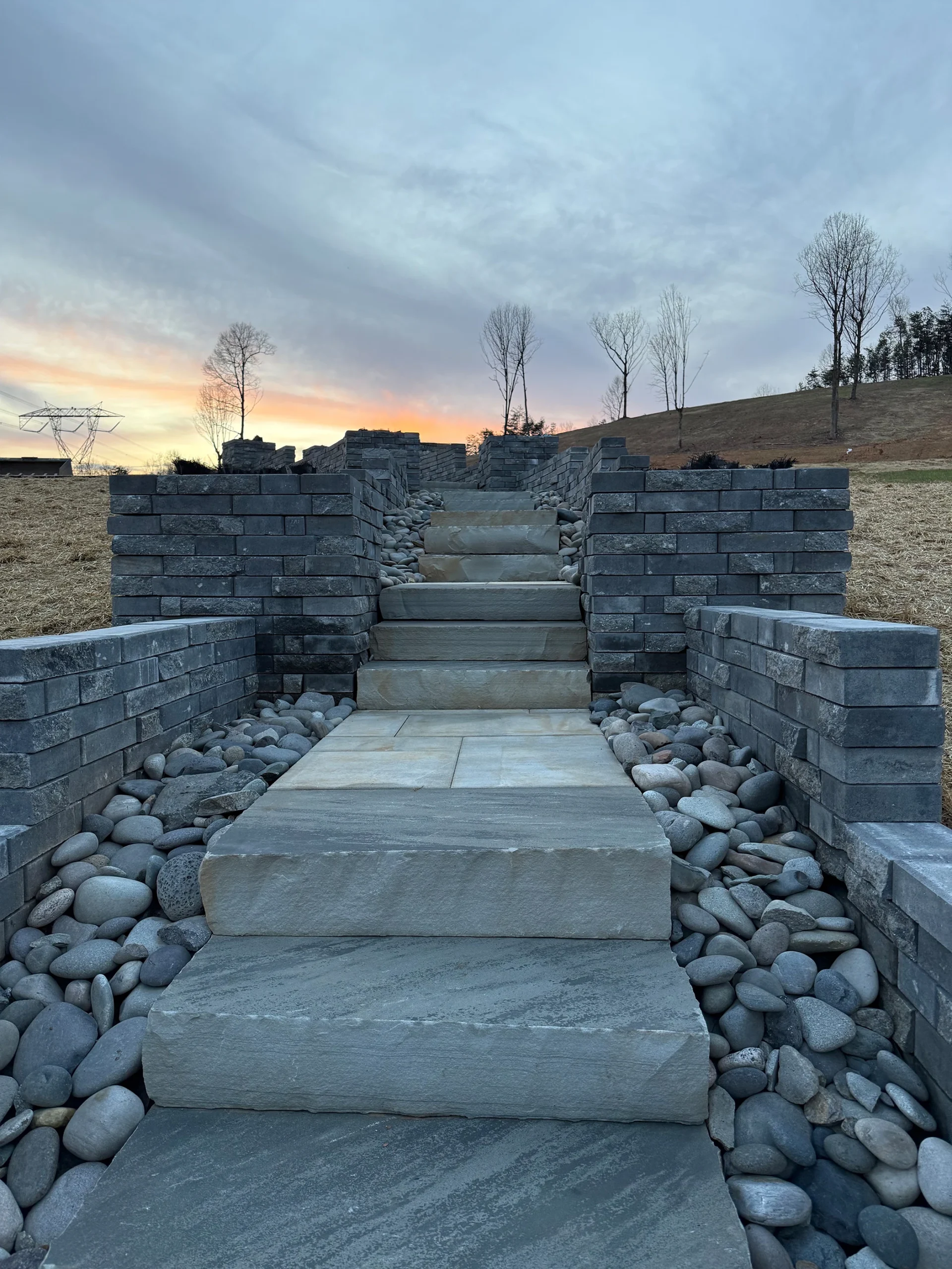 Tiered stone retaining wall system with integrated staircase in Canton Georgia by Kaizenscapes