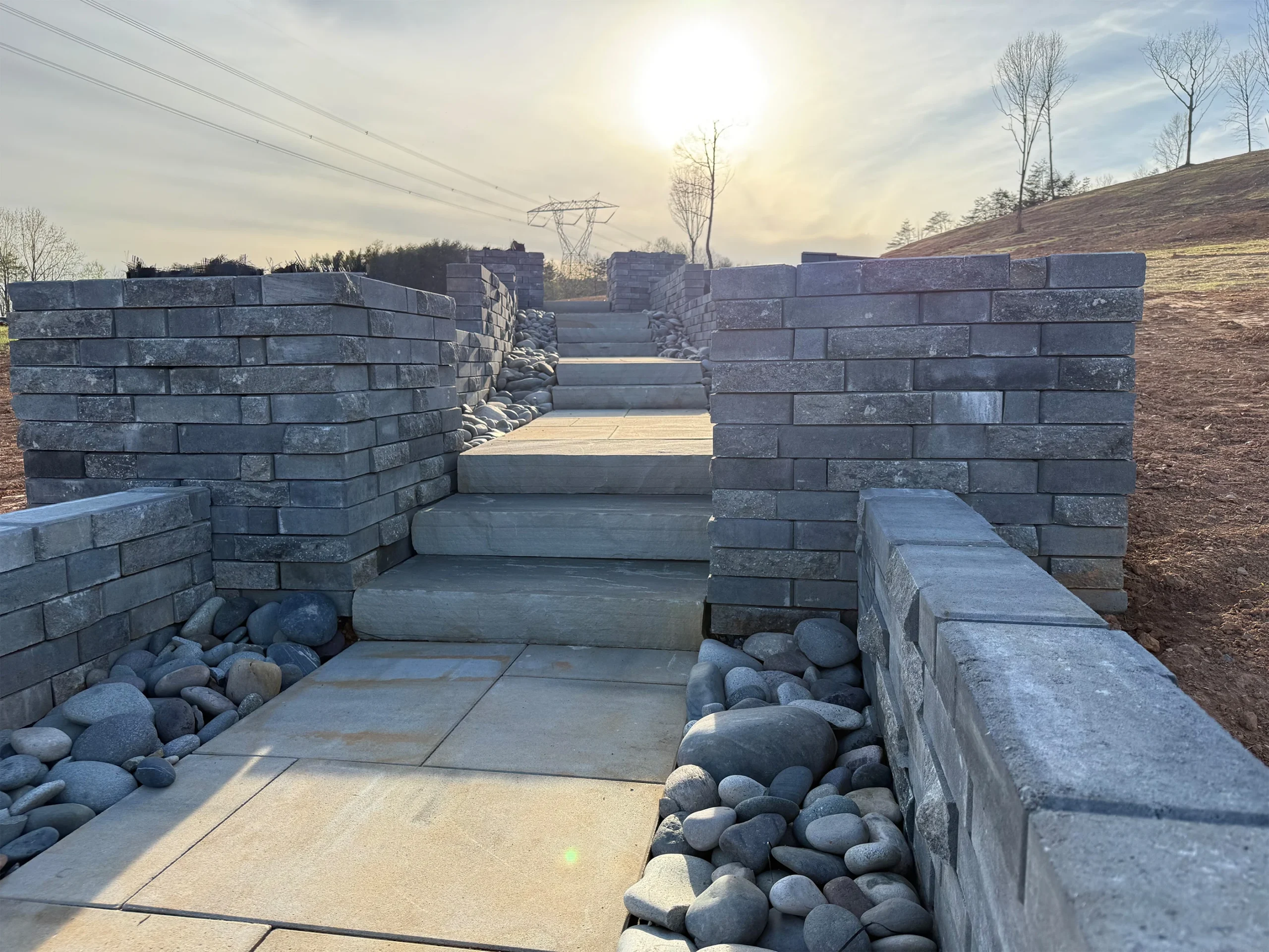 Mixed aggregate drainage with rip-rap and river rock installed around retaining wall in Canton Georgia