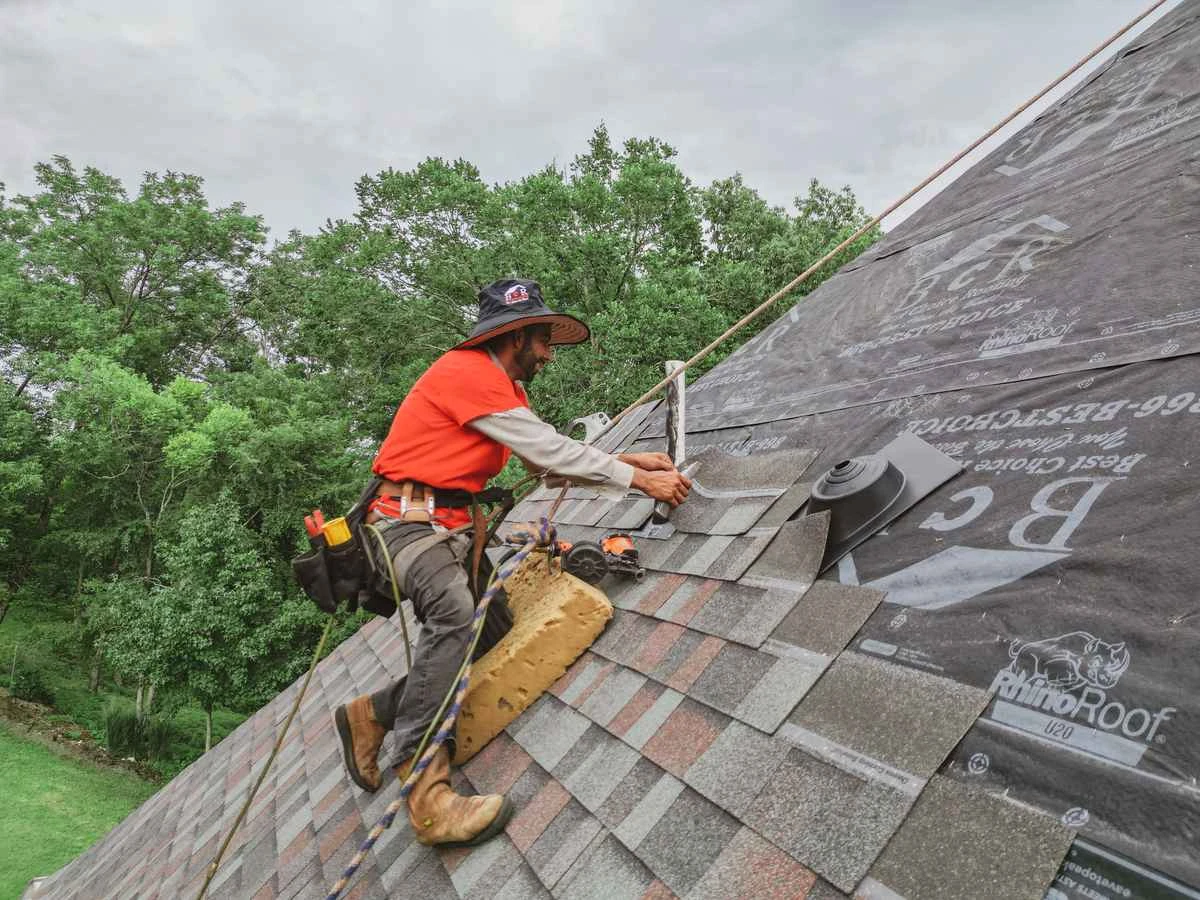 Roofer inspecting hail damage on a Kennesaw home